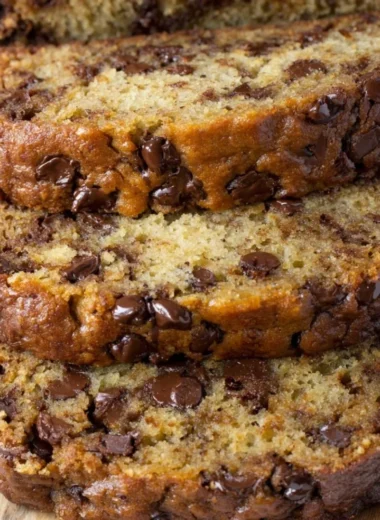 Moist and delicious chocolate chip banana bread sliced on a wooden cutting board.