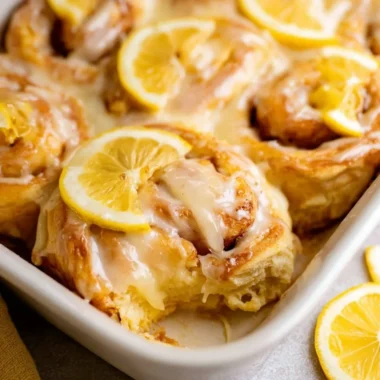 Freshly baked lemon rolls drizzled with icing sugar, ready to be served.