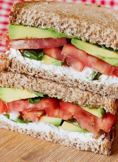 Delicious Tomato Avocado Sandwich on whole grain bread with fresh vegetables.