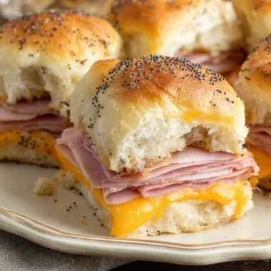 Baked ham and cheese sliders served on a platter with sesame seed tops.