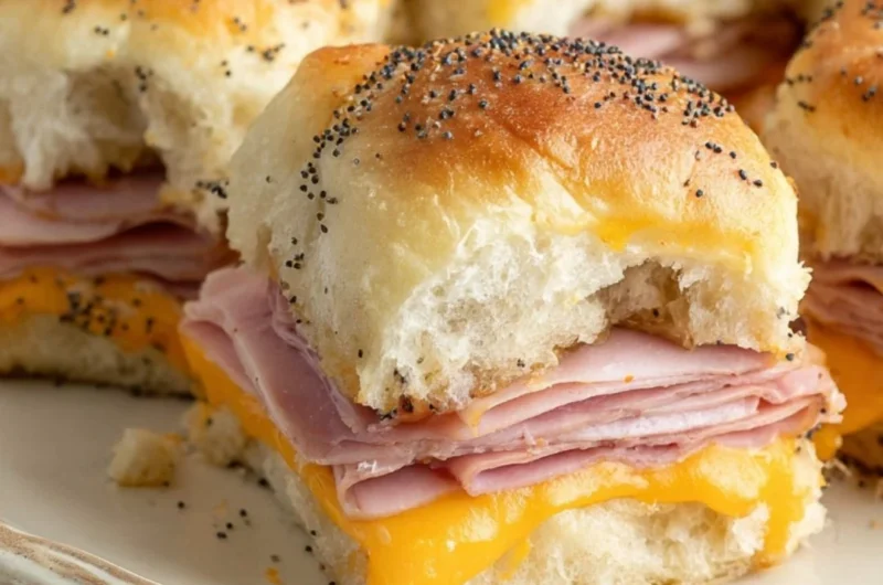 Baked ham and cheese sliders served on a platter with sesame seed tops.