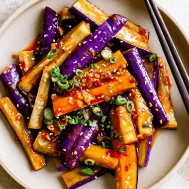 Spicy eggplant stir fry with vibrant vegetables and herbs in a skillet