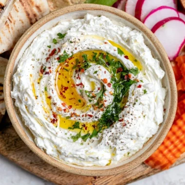 Delicious whipped feta dip served in a bowl with fresh herbs and pita chips