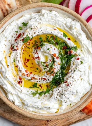 Delicious whipped feta dip served in a bowl with fresh herbs and pita chips