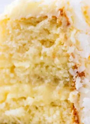 Coconut cake topped with cream cheese frosting on a decorative plate