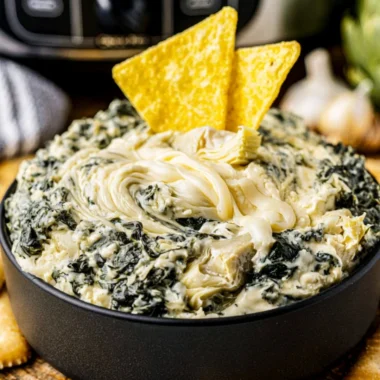 Creamy Crock Pot spinach artichoke dip served in a bowl with fresh herbs.