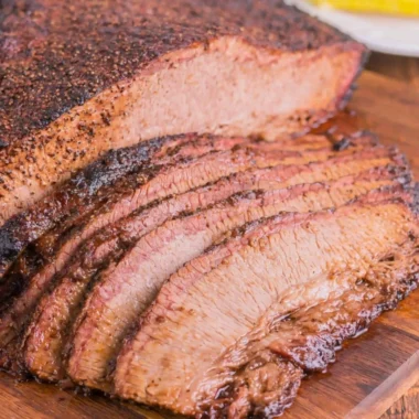 Juicy oven-cooked brisket served on a cutting board with fresh herbs.