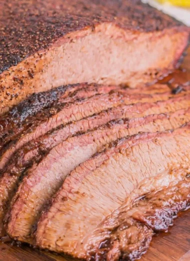 Juicy oven-cooked brisket served on a cutting board with fresh herbs.
