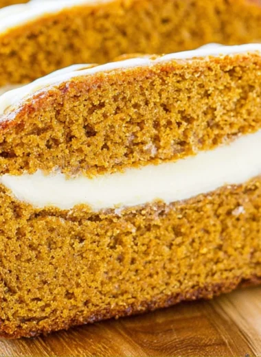 Delicious pumpkin bread with cream cheese frosting on a wooden table