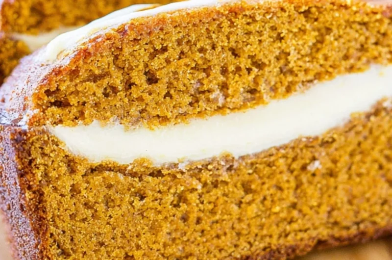 Delicious pumpkin bread with cream cheese frosting on a wooden table