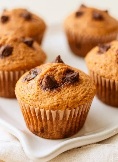 Freshly baked pumpkin chocolate muffins on a rustic wooden table